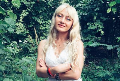 Portrait of beautiful young woman standing against plants