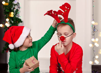 Portrait of smiling girl playing with christmas tree at home