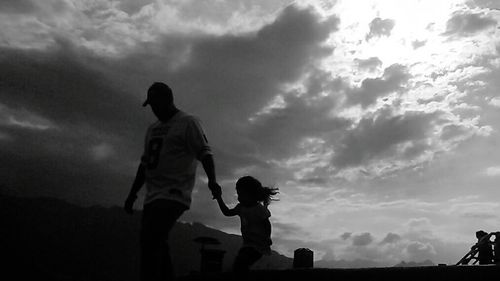 Low angle view of people against cloudy sky