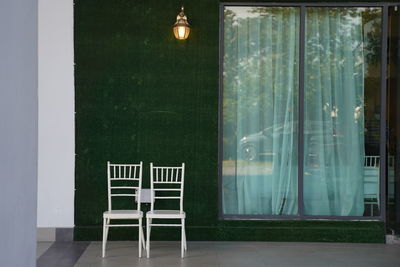 Empty chairs and table against window