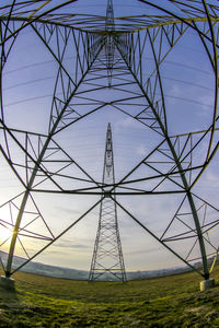 Low angle view of electricity pylon on field against sky