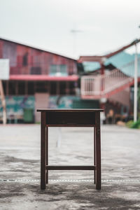 Empty chairs and tables by street against buildings in city