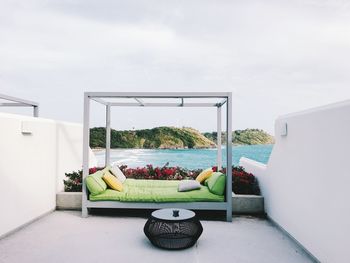 Relaxing sofa by sea against sky