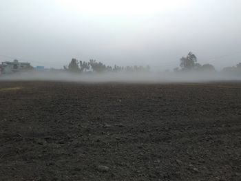 Scenic view of field in foggy weather against sky