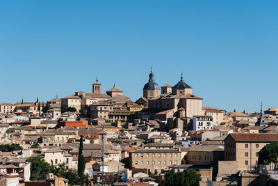 View of buildings in city against clear blue sky