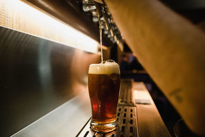 Cropped hands of man pouring beer from tap in glass