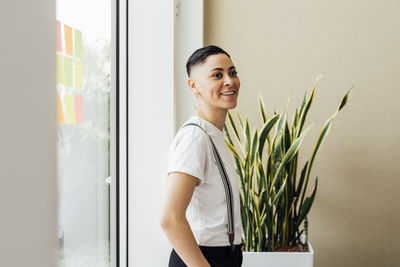Female entrepreneur smiling while standing by window in office