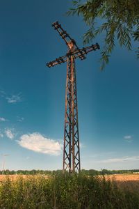 Low angle view of old power line on field against sky