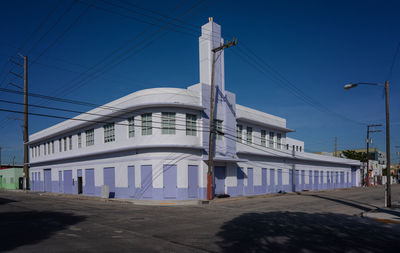 Street by buildings against clear blue sky