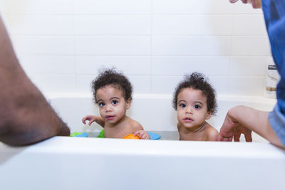 Cropped image of parents bathing daughters together in bathtub