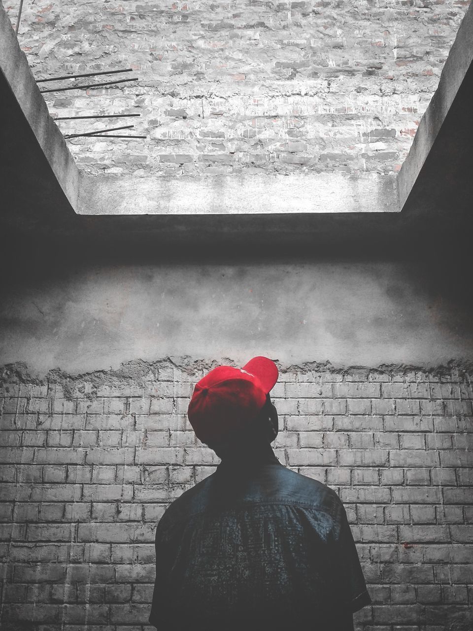 REAR VIEW OF MAN STANDING BY WALL