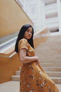 Low angle view portrait of young woman standing on staircase