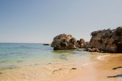 Rocks on beach against clear sky