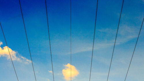 Low angle view of power lines against blue sky