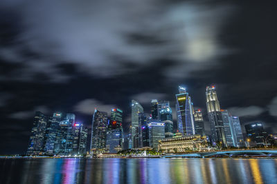 Illuminated modern buildings in city against sky at night