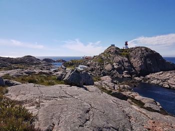 Man standing on cliff by mountain against sky