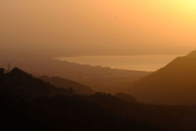 Scenic view of silhouette mountains against orange sky