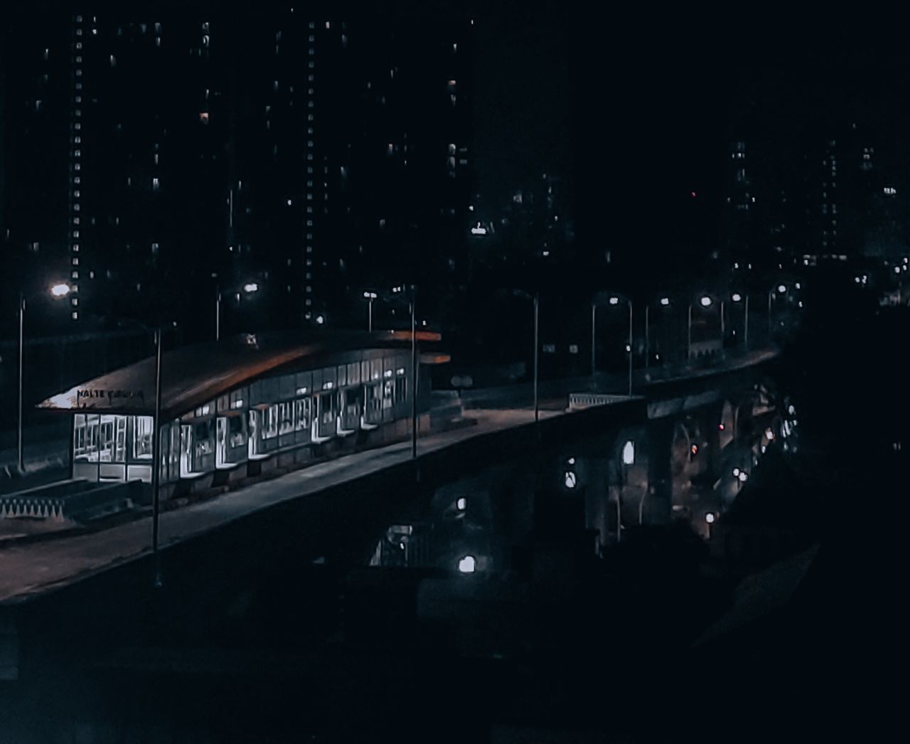 HIGH ANGLE VIEW OF ILLUMINATED BRIDGE OVER STREET IN CITY AT NIGHT