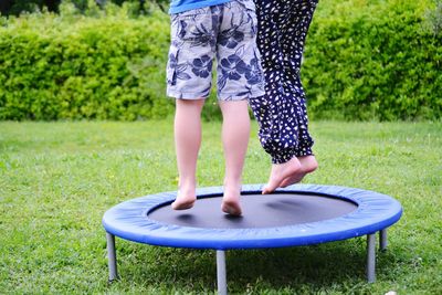 Low section of siblings jumping on trampoline at yard