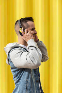 Portrait of a young cool man over yellow background.