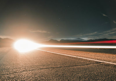 Light trails on field against sky at sunset