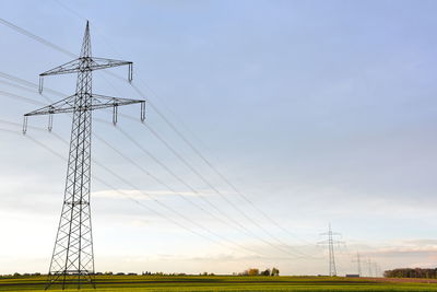 Low angle view of electricity pylon on field against sky