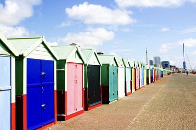 Colorful beach huts against cloudy sky