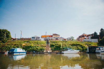 Buildings by river against sky