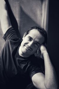 Portrait of young man leaning against wall at home
