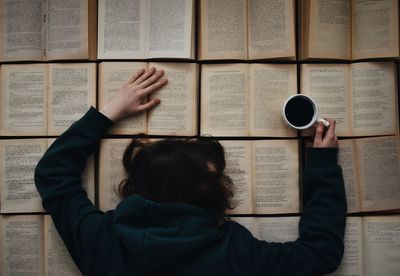 Directly above shot of woman having coffee while leaning on books
