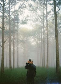 Woman photographing in forest