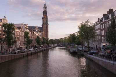 Canal amidst city against sky during dusk