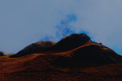 Low angle view of volcanic mountain against sky