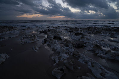 Scenic view of beach against sky at dusk