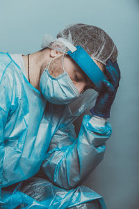 Portrait of man wearing mask against blue wall