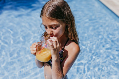 Midsection of woman drinking water in swimming pool