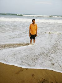 Portrait of young man standing in sea against cloudy sky