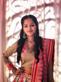 Portrait of smiling young woman standing against wall