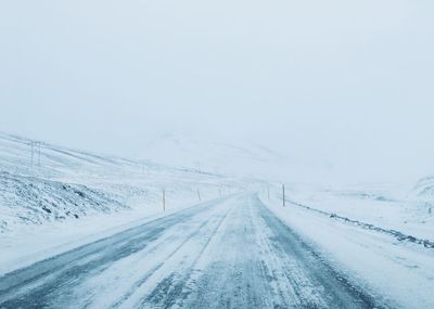 Snow covered road against sky during winter