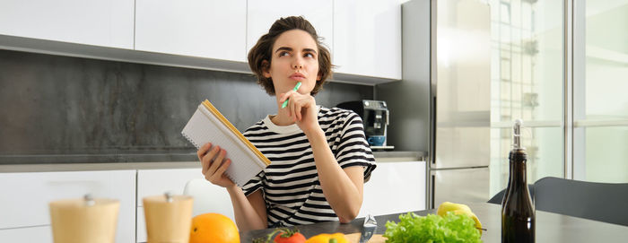 Portrait of young woman using mobile phone while sitting on table