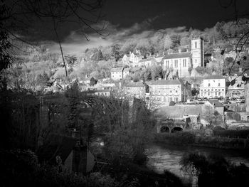 Trees and townscape against sky at dusk