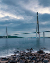 Bridge over sea against cloudy sky