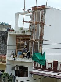 Low angle view of crane at construction site against sky