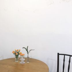 Flower vase on table against wall at home