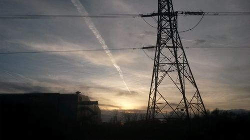 Low angle view of electricity pylon against cloudy sky