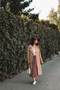 A happy single woman in elegant clothes walks in an fall park and in the forest in autumn outdoors