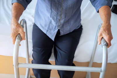 Midsection of man with walker standing at home