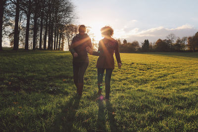 Friends walking on grassy field at park