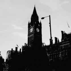 Low angle view of clock tower amidst buildings in city