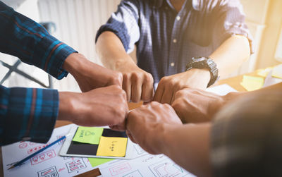 Midsection of people holding hands on table